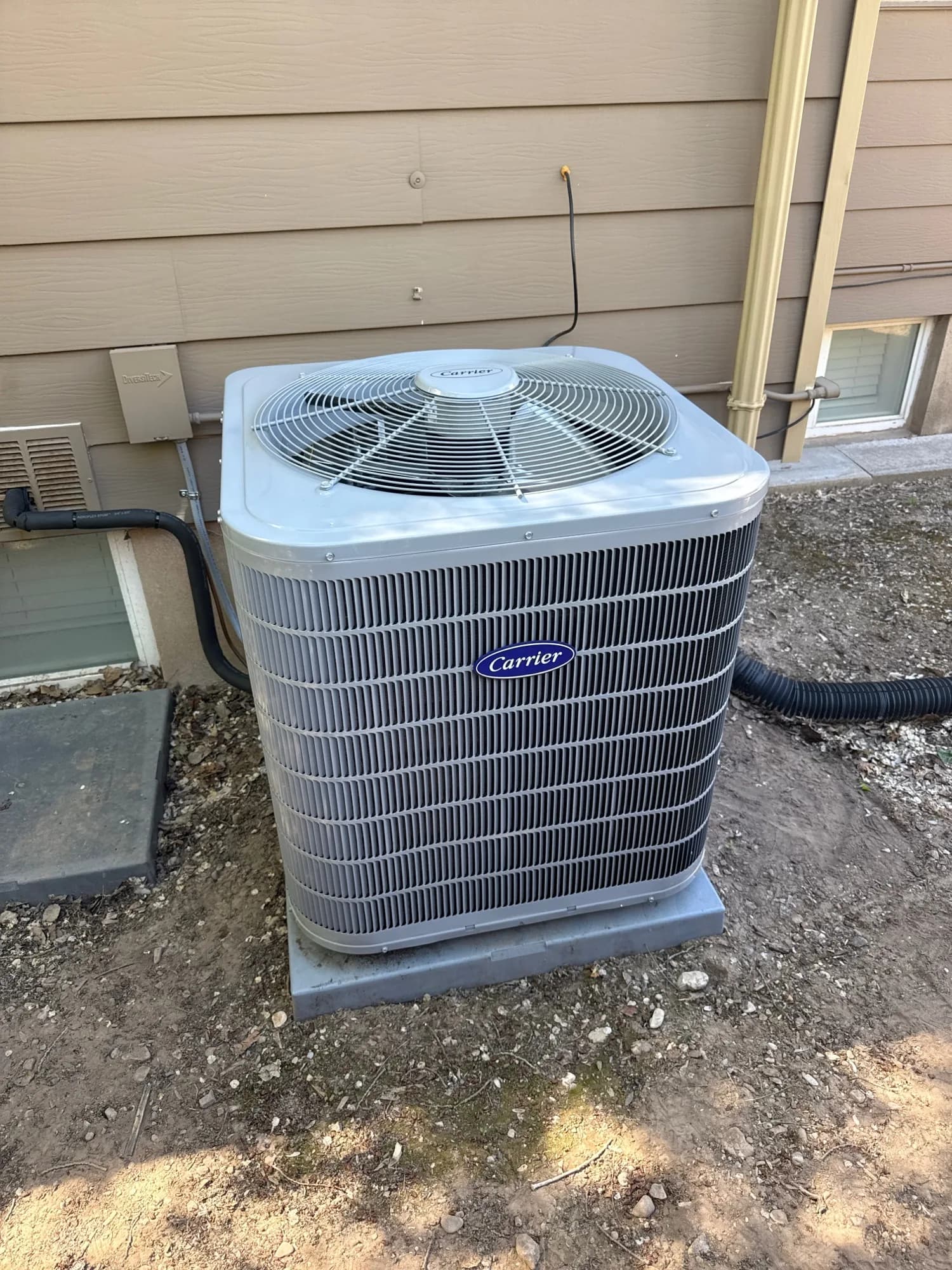New Carrier air conditioner installed on a pad beside a Salt Lake Valley home