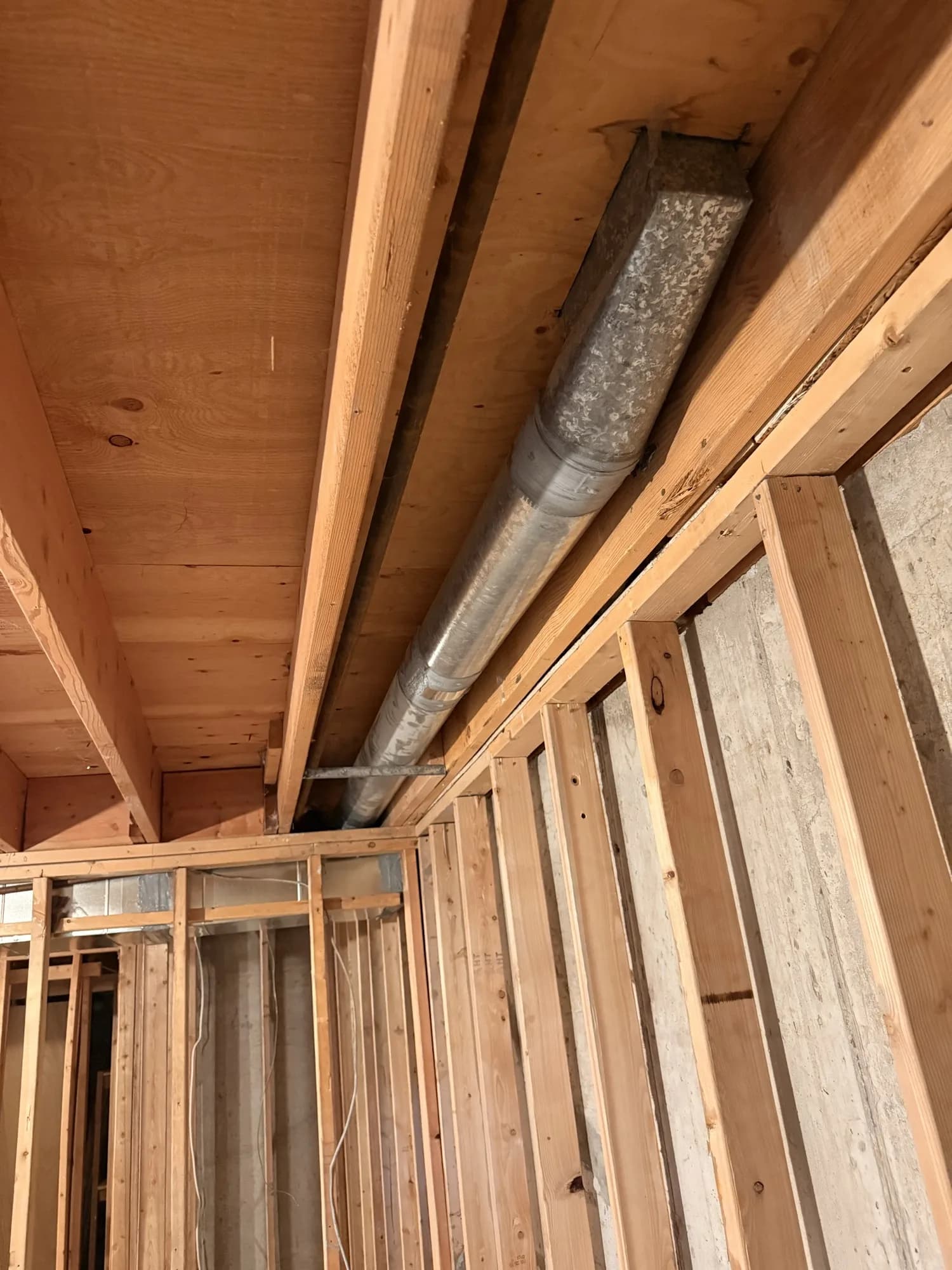 Duct branch runs fitted between basement framing before drywall