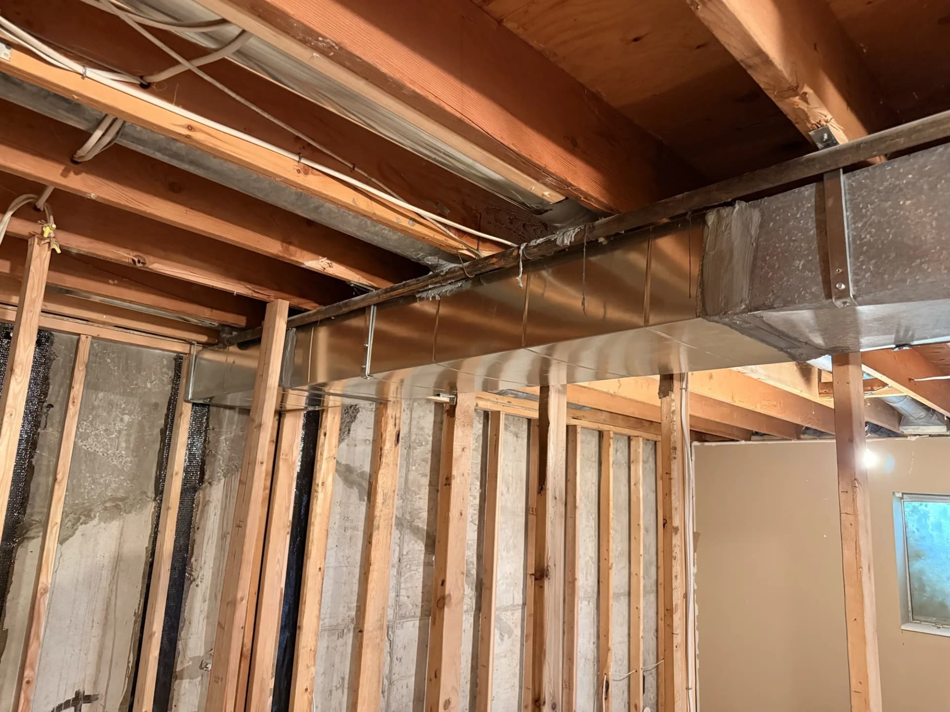 New duct trunk and branch lines roughed in across a basement ceiling